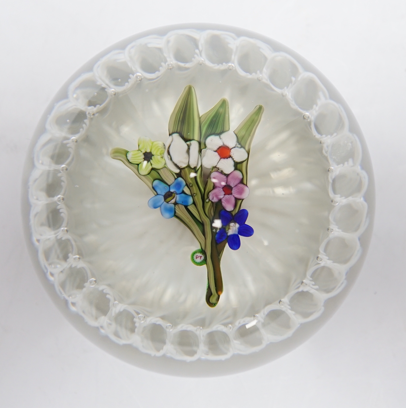 A Paul Ysart ‘small flower bouquet’ glass paperweight, Caithness or Harland period, ‘PY’ cane, white latticino ground, fire polished pontil, 7cm